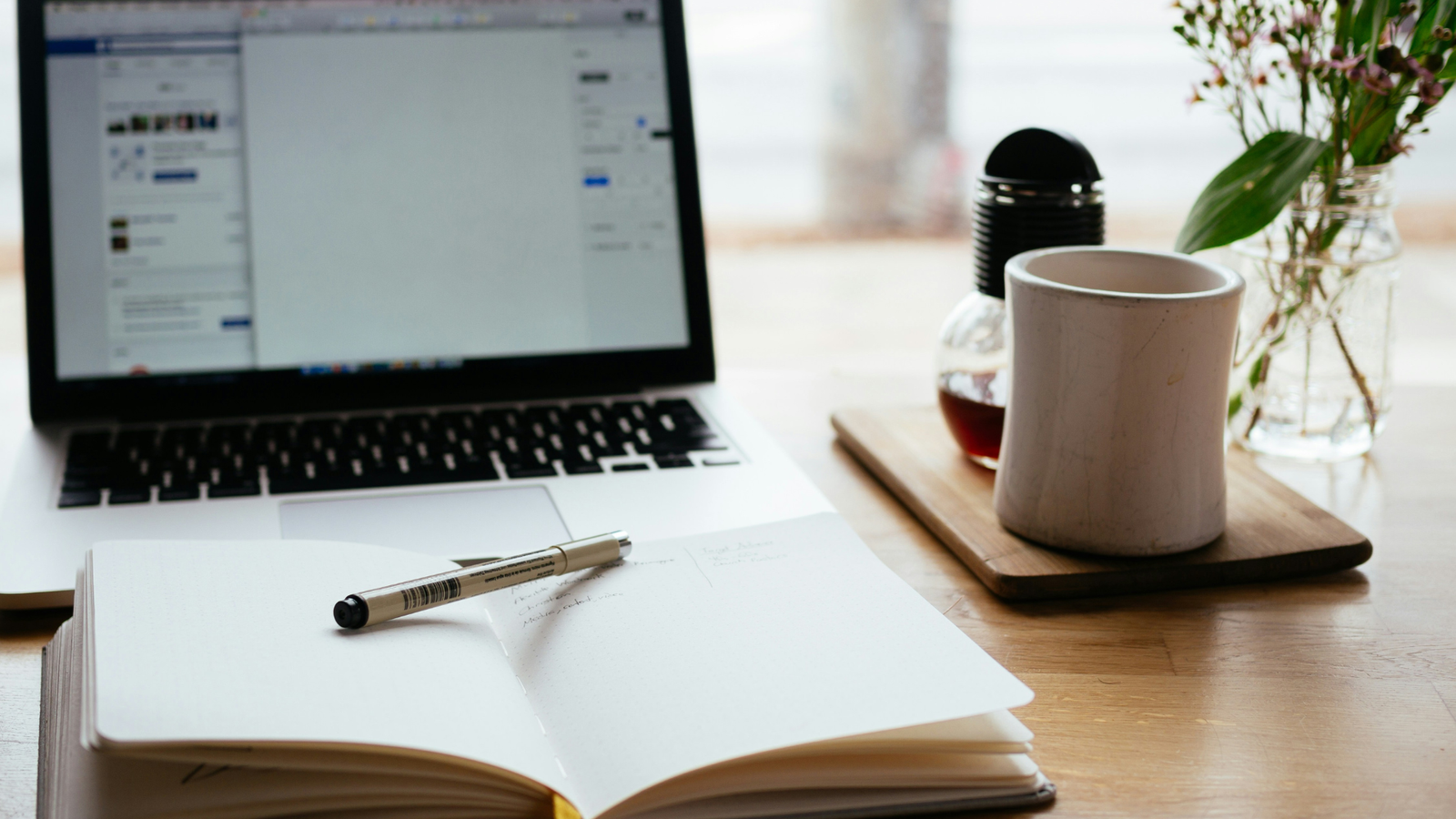Sustainability Content Marketing UK - An image of a notepad and laptop on a desk with a plant.